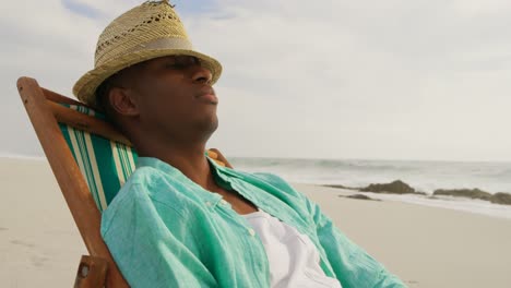 Side-view-of-African-american-man-sleeping-in-a-sun-lounger-on-the-beach-4k