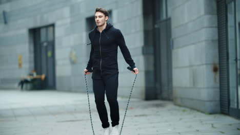 Fit-man-training-jump-exercise-on-skipping-rope-on-workout.-Sporty-man-jumping