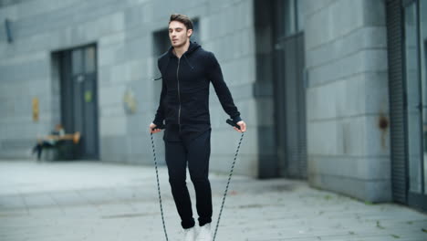 fit man training jump exercise on skipping rope on workout. sporty man jumping