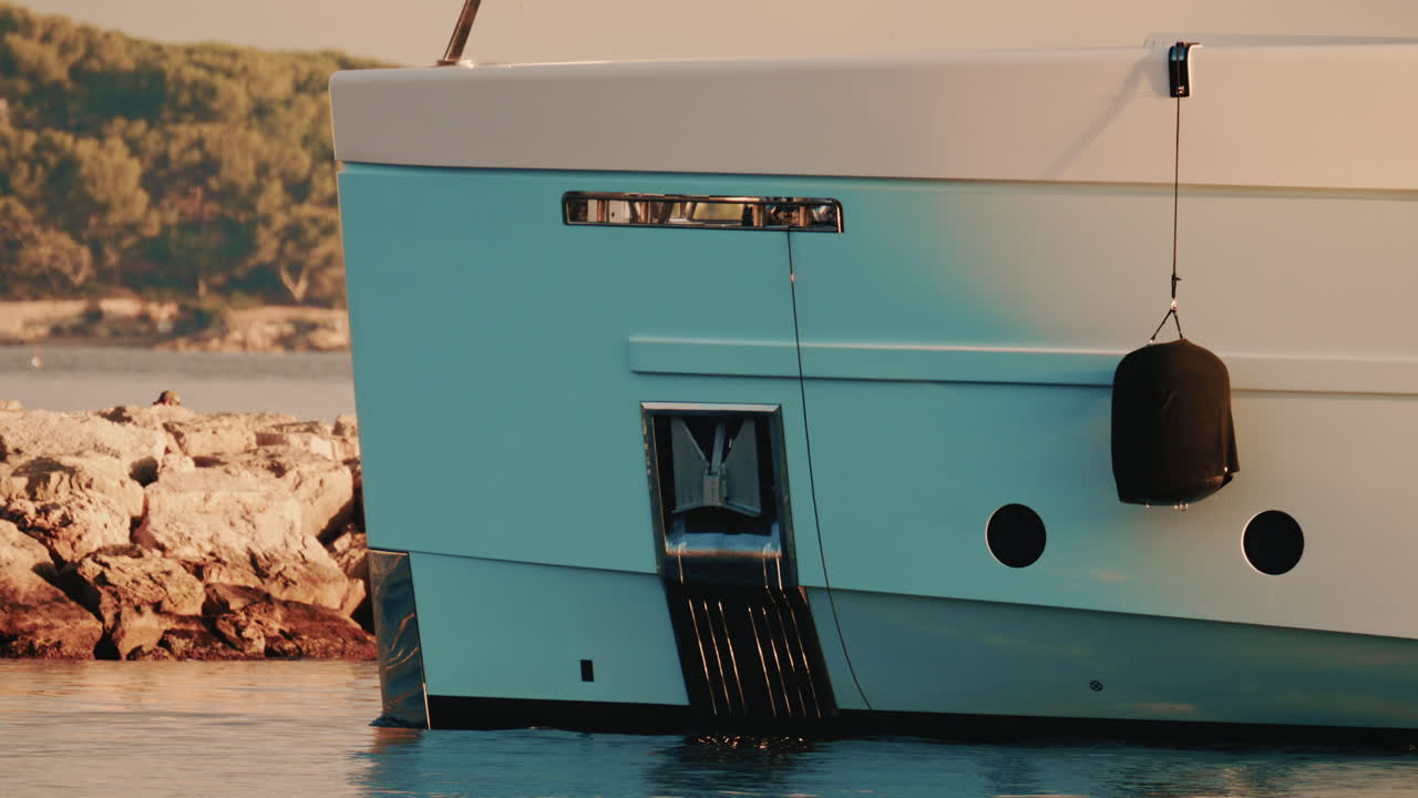 Primo piano dettagliato dello scafo di uno yacht di lusso con un parabordo nero appeso e la linea di galleggiamento visibile