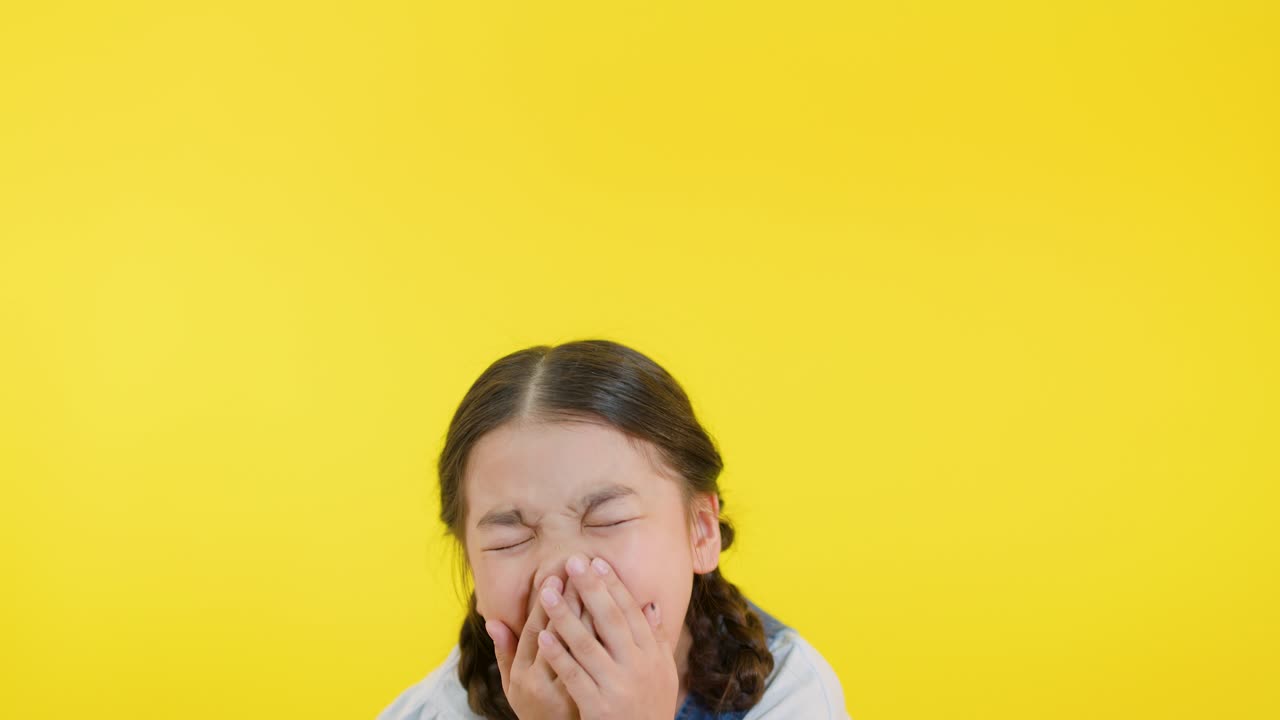 Girl with braids laughs, covers mouth, and smiles in bright, evenly lit studio setting