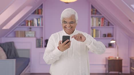 Happy-Indian-old-man-scrolling-through-phone