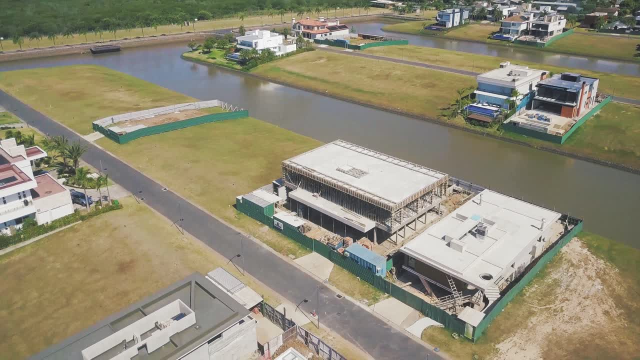 Modern House Buildings Under Construction In Ponta Da Figueira Peninsula In Brazil Surrounded By Brown Navigable Canals On A Sunny Day - Aerial Shot