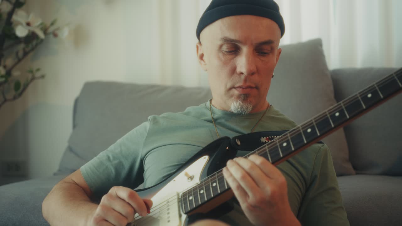Pria Bermain Gitar Listrik dengan Fokus dan Semangat di Rumah