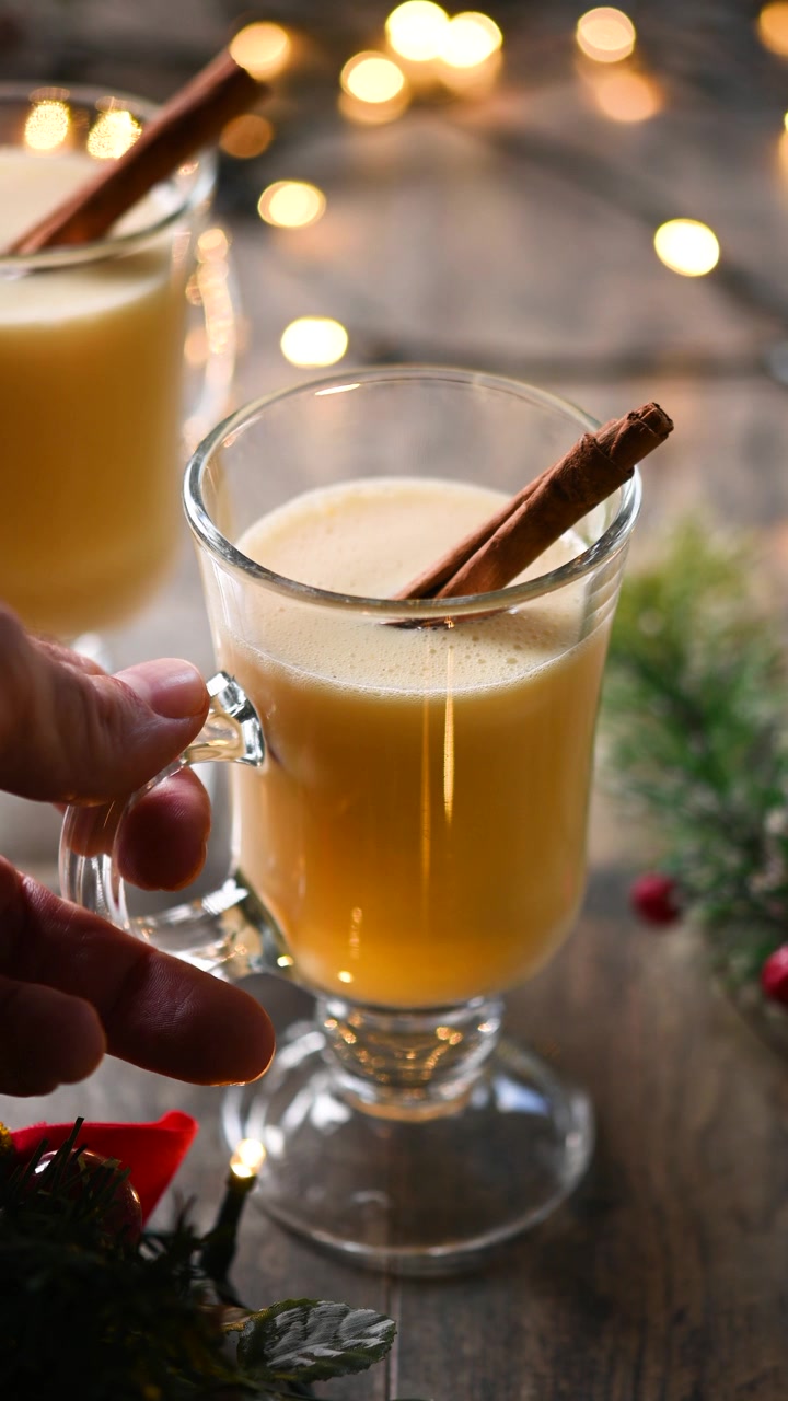 Prenant un verre de lait de poule sur la table de Noël.