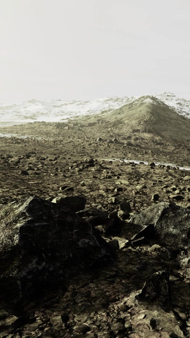 Paesaggio roccioso con montagne innevate sullo sfondo a mezzogiorno.