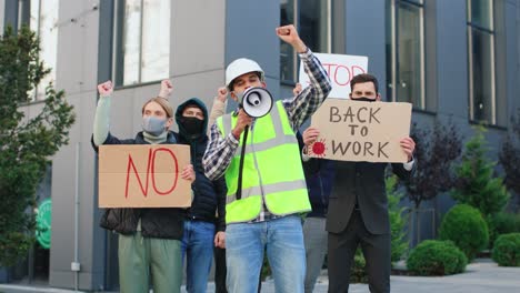 people protesting against covid 19 while holding singboards and yelling in the street