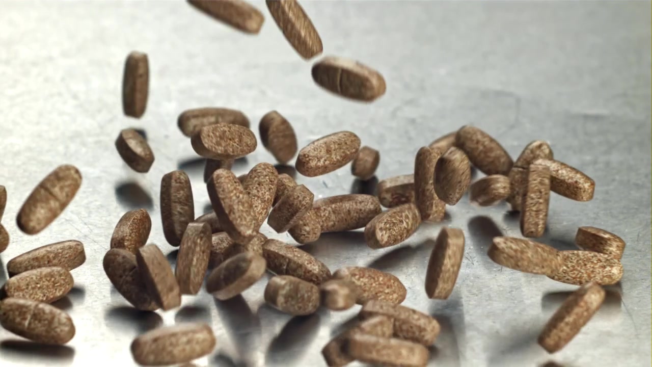 Brown Pills Falling in Slow Motion onto a Metallic Surface