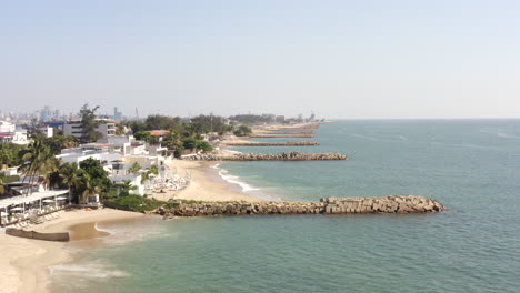 beach with breakwaters and beachfront hotels in luanda island, angola. - aerial pullback shot