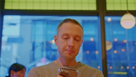 caucasian-white-male-man-buy-boy-model-with-blue-eyes-and-bright-hair-is-sitting-in-a-cafe,-restaurant-and-talking-with-a-cellphone