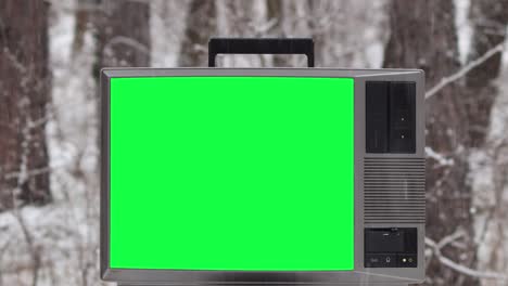 old vintage tv with green screen in forest white is snowing