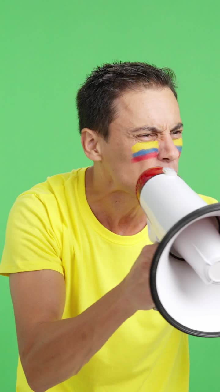 Excited man with colombian flag on face using a megaphone