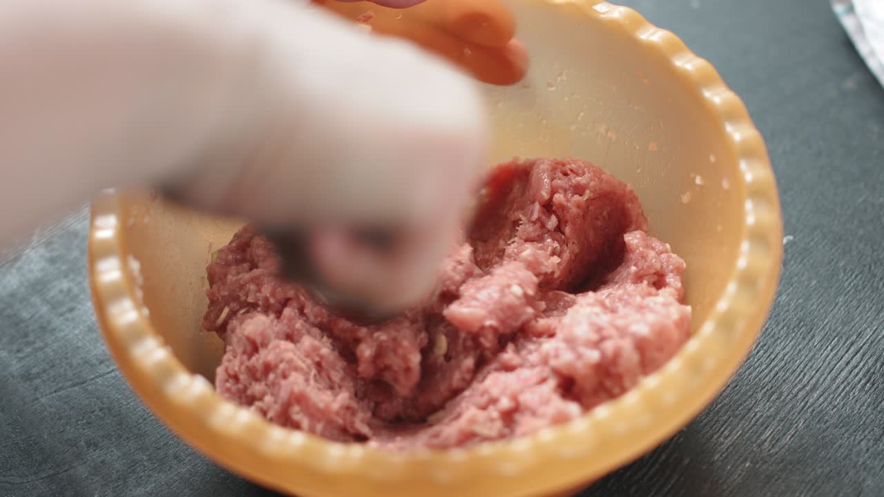 dos manos haciendo albóndigas de carne.