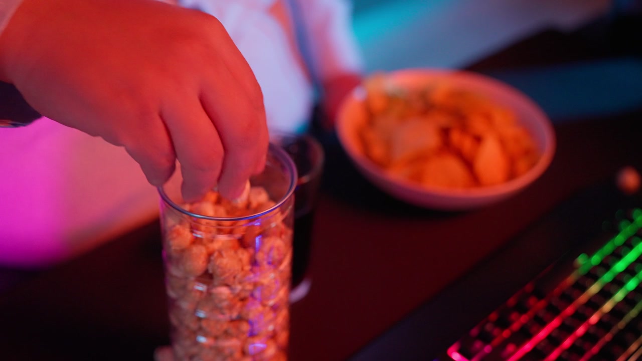Primo piano di una mano che prende popcorn da un barattolo alla scrivania da gaming