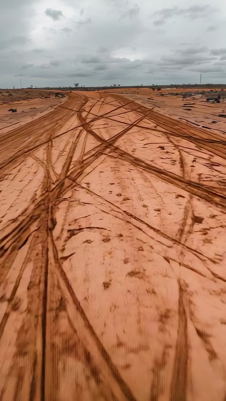 Vertical video: Driving off-road vehicle across loose sandy desert plain with tire tracks