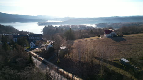 Polanczyk-village-and-Bieszczady-Mountains-in-Lesko-County,-on-the-banks-of-Solina-Lake-in-Poland-countryside--aerial-dolly-on-sunset