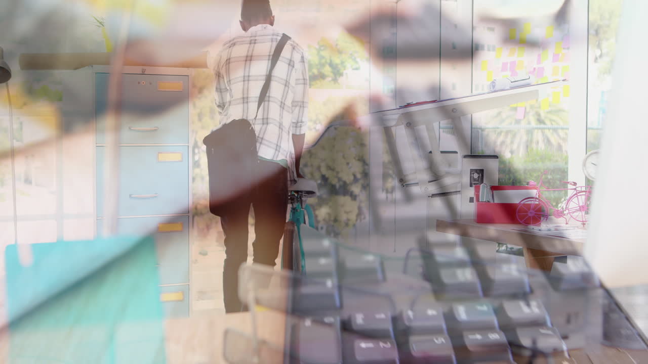 animación de un hombre de negocios afroamericano con bicicleta sobre un hombre caucásico usando el teclado