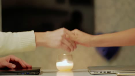 las manos de la pareja adulta terminan de trabajar en las computadoras portátiles y las manos se estrechan de cerca