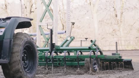 man working with his atv to smooth out sand from the horse riding arena