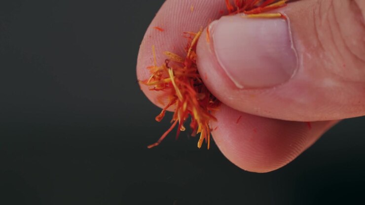 Close-up of Hand Sprinkling Red Saffron Threads