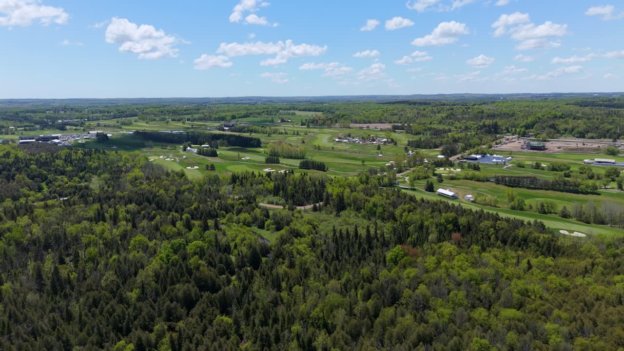 Aerial pull-out of forested Osprey Valley golf course in sunny Canada