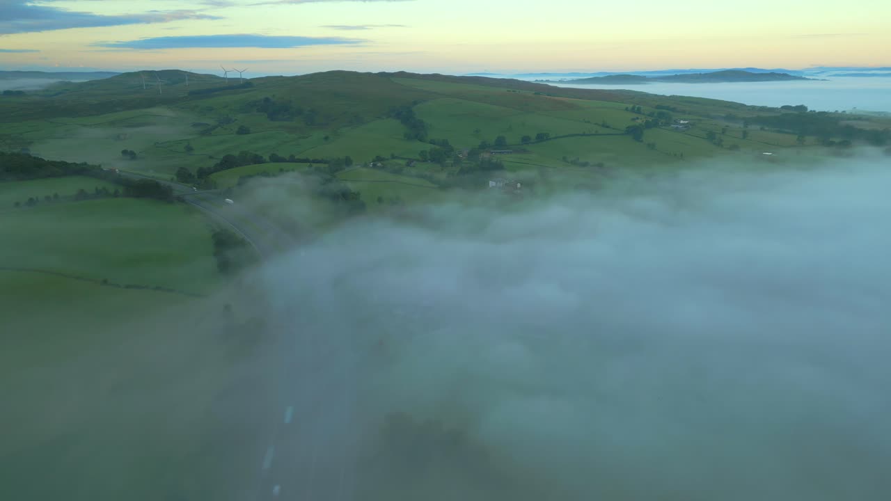 volando alto sobre la niebla de la autopista m6 con banco de niebla y colinas verdes al amanecer
