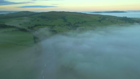 Volando-Alto-Sobre-La-Brumosa-Autopista-M6-Con-Banco-De-Niebla-Y-Colinas-Verdes-Al-Amanecer