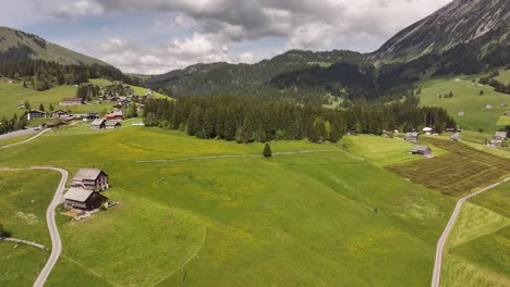 aerial view of swiss countryside near amden, peaceful village homes, green pastures and mountain ranges under cloudy skies
