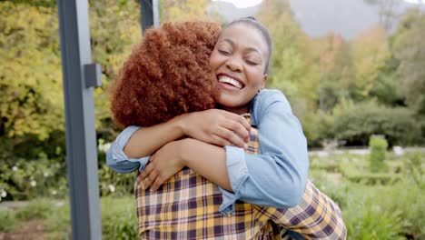 happy diverse couple embracing and smiling in garden, in slow motion