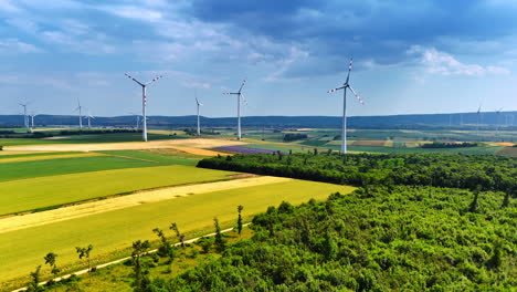 vast wind farm under blue sky. wind turbines tower over fields and forests, harnessing renewable energy in a vibrant rural landscape