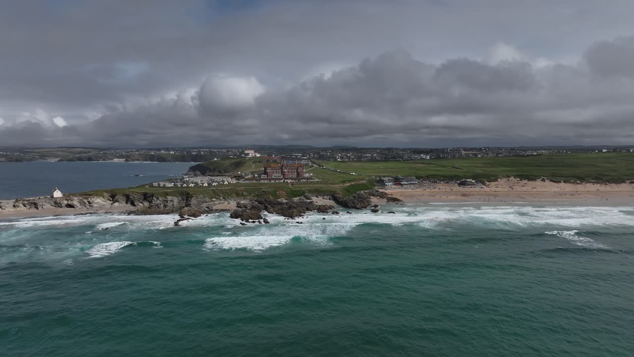 Establishing shot showing the Headland Hotel and a busy Fistral beach, Newquay
