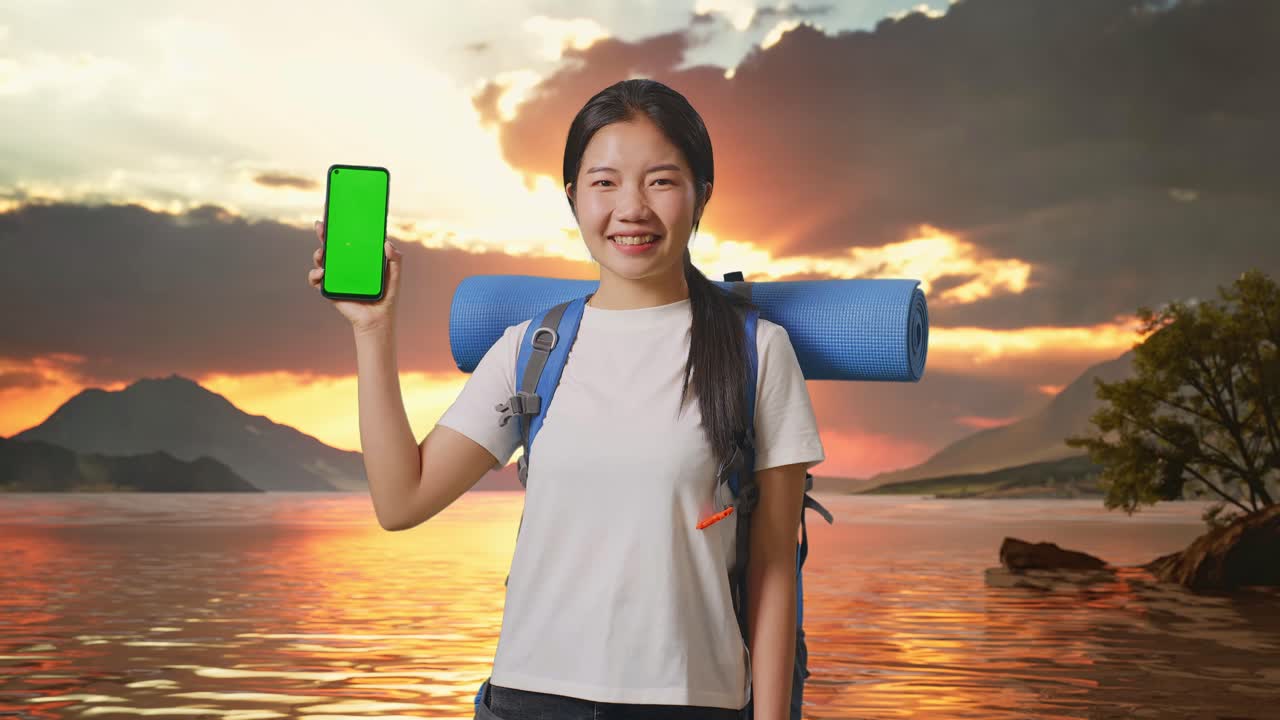 Woman with backpack and phone at sunset