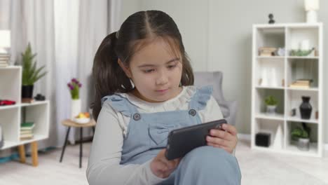 young girl on asd spectrum gaming on mobile phone in bedroom at home