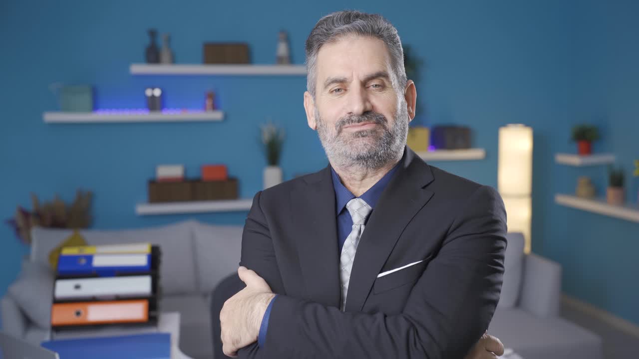 집에서 카메라를 쳐다보고 팔을  ⁇ 는 자신감 넘치는 긍정적인 사업가입니다.