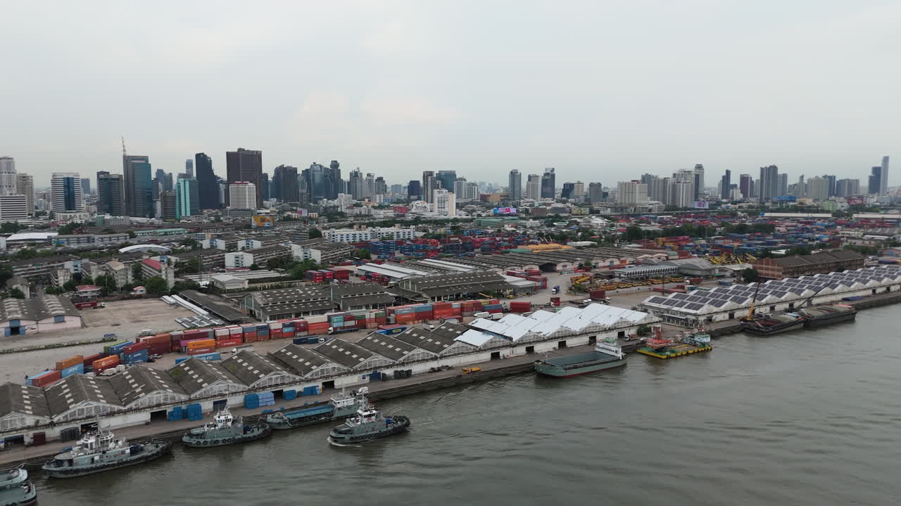 Aerial View Of Khlong Toei Port On Chao Phraya River In Bangkok, Thailand, With City Skyline Revealed In Background. panning tilt-up shot