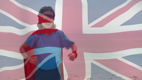 kind im superhelden-kostüm mit union jack-flagge-animation über strand-hintergrund