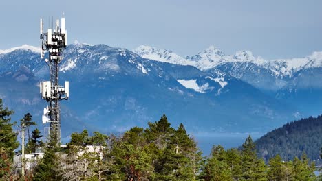 torre de comunicaciones con montañas de nieve en el fondo en la bahía de la herradura, oeste de vancouver, canadá