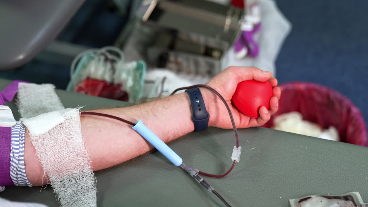 Blood is taken from a male donor. Medical machine is waving the plastic bag at backdrop. Transfusion and donation of blood concept.