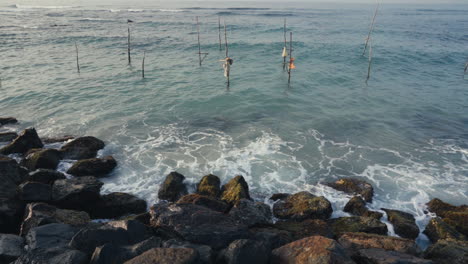 Wellen-Plätschern-An-Der-Felsigen-Küste-Mit-Auf-Dem-Meer-Gepflanzten-Holzstelzen-In-Weligama,-Matara,-Sri-Lanka