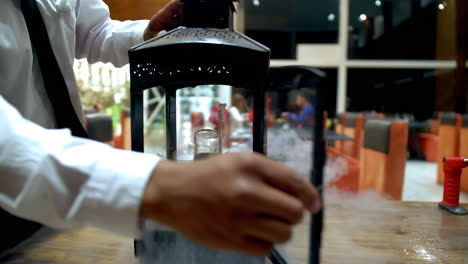 el camarero abre la jaula de velas con vapor y cóctel de mula de moscú dentro