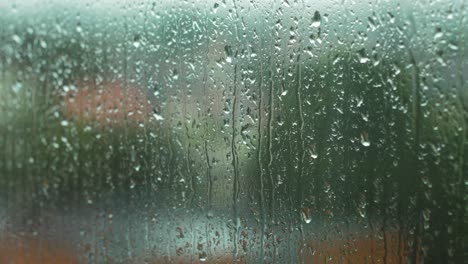 rain drops sliding slow on window glass in rainy day, de-focused city in background,medium closeup shot