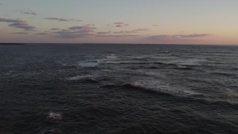 Peaceful-dusk-last-light-over-whitecaps-as-waves-break-on-ocean-and-mist-rises,-Chincoteague-Island-Virginia,-slow-motion