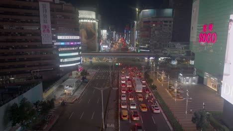 traffic scene in downtown of taipei city, taiwan at night. modern skyline with crossing train on bridge. digital commercial advertising on buildings. aerial wide shot.