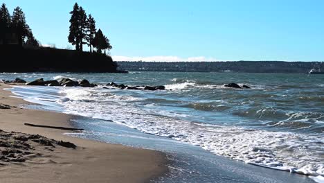 small waves calm rooling at the beach while the sand is drying up immidetly on a bright summer day in stanley park