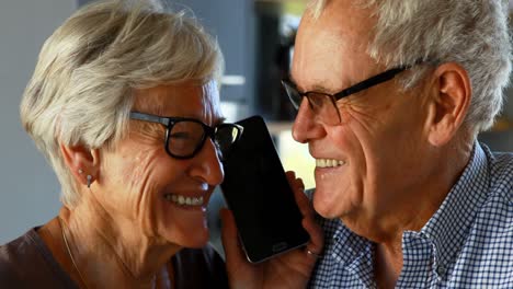 Senior-couple-talking-on-mobile-phone-in-kitchen-4k