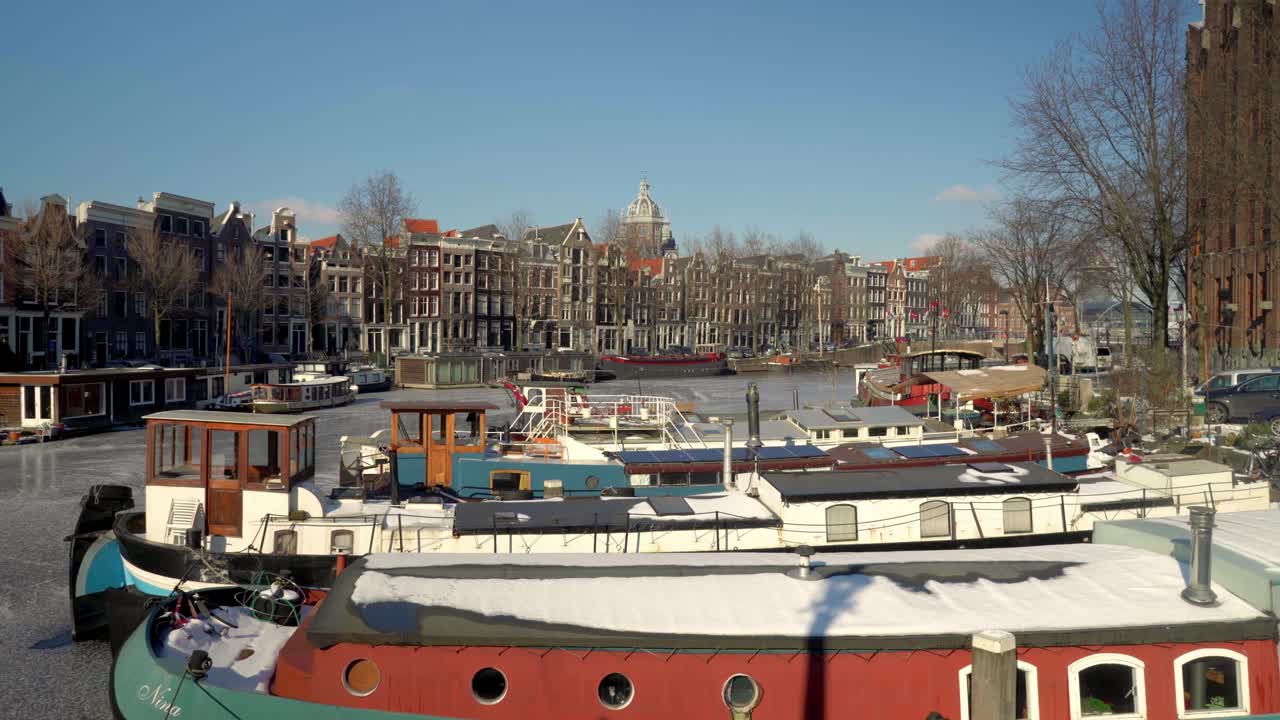 Abandoned and silence around the streets of Amsterdam in winter with houseboats in frozen canal, The Netherlands