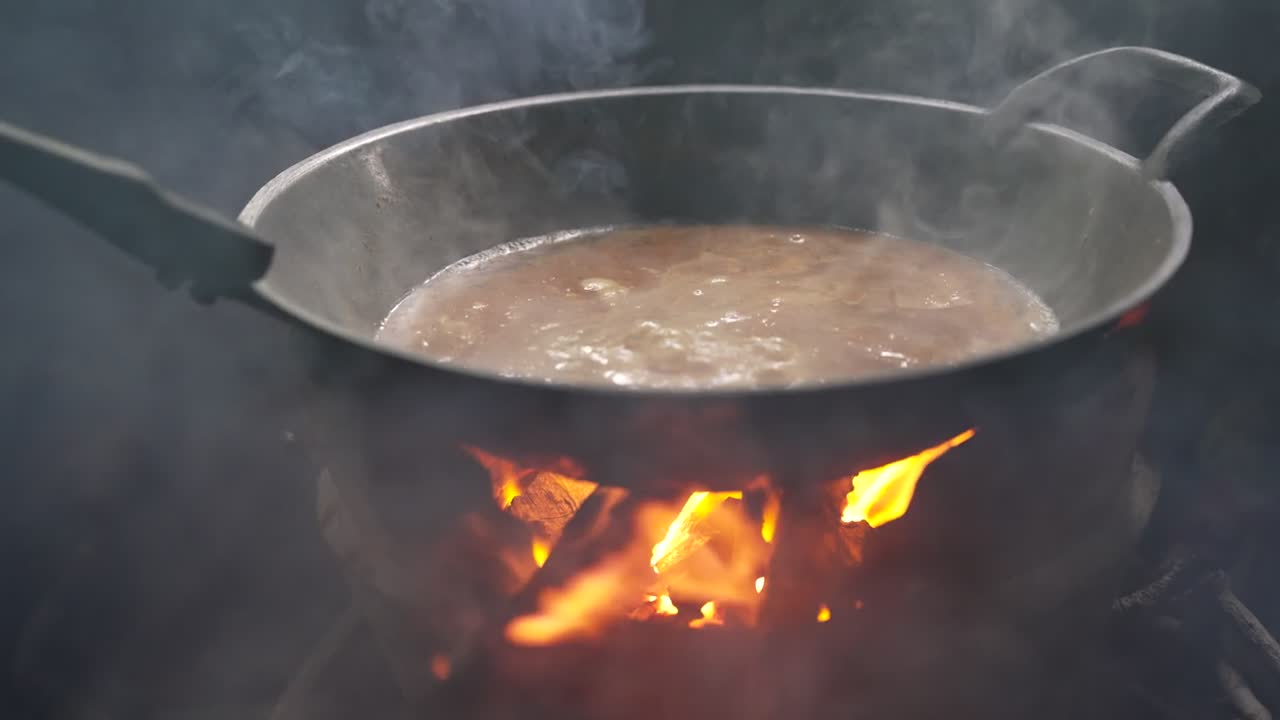 Traditional Thai cooking over open wood fire in a rustic kitchen, ideal for culinary and cultural footage