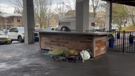 homeless person sleeping on the floor in a covered food stall area in ashland, oregon, usa