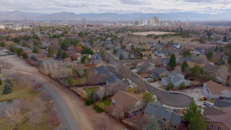 Slow-pull-away-from-subdivision-in-Reno,-Nevada-with-city-skyline-and-mountains-on-the-horizon-on-a-pretty-winter-day