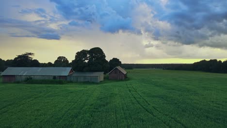 farm houses and farm fields on a cloudy day near hjo, sweden - aerial drone shot